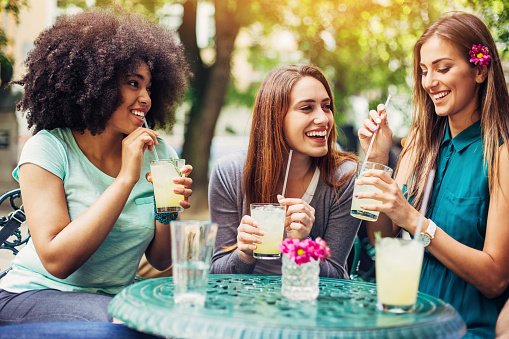 Group of attractive young women sitting in a bistro, having iced drinks and chatting