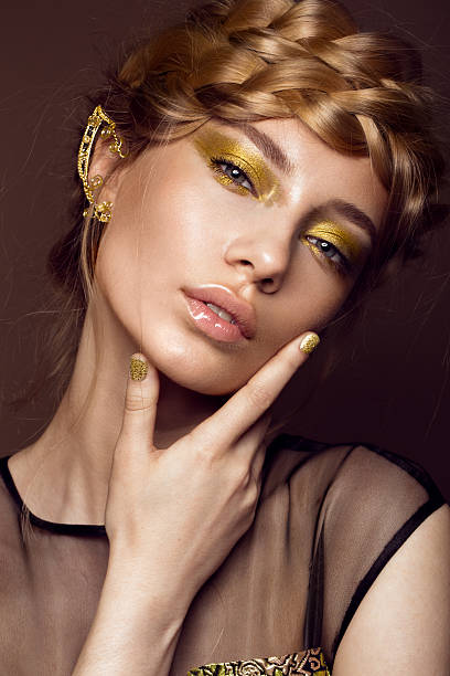 красивая девушка в платье золото с творческим макияж и заплетенными колосом завязками - gold hair стоковые фото и изображения