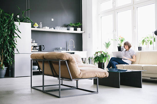 woman sit on couch in loft and work at laptop