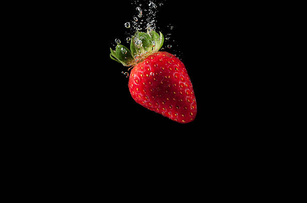 istock red strawberry splashing in water isolated on black 533704092