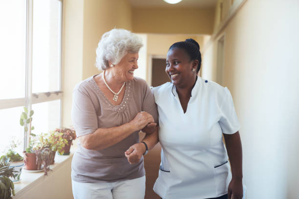 笑顔の介護士と年配の女性を歩く - patient doctor african descent hospital ストックフォトと画像