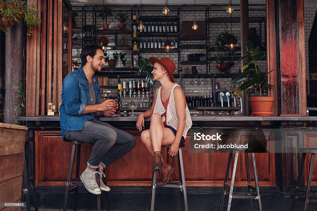 Young couple sitting at cafe counter Shot of young couple sitting at cafe counter. Young man and woman at coffee shop. Bar - Drink Establishment Stock Photo