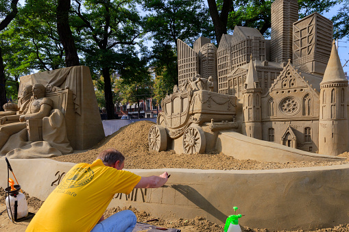 The Hague, Netherlands - September 16, 2014: artist working on a sandcastle on Buitenhof in The Hague during Prinsjesdag depicting the characteristic Knights' Hall, the Mauritshuis, the Golden Coach and the cities modern office buildings.