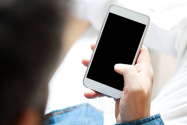 Young man using cell phone Young man using cell phone, shallow depth of field man looking at phone over shoulder stock pictures, royalty-free photos & images