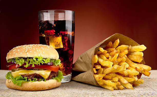 cheeseburger con drink di cola e patatine fritte rosso in primo piano - burger french fries cheeseburger hamburger foto e immagini stock