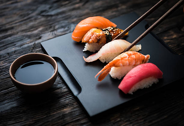 close up of sashimi sushi set with chopsticks and soy - nigiri fotos stockfoto's en -beelden