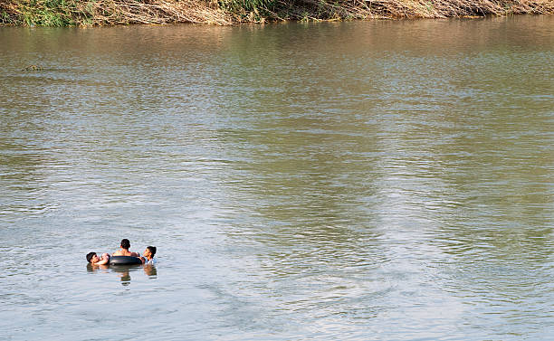 Boys swimming in Euphrates River in Deir ez-Zur, Syria Deir ez-Zur, Syria - June 20, 2010: Three boys share an inner tube on the Euphrates River in Deir ez-Zur, Syria. euphrates syria stock pictures, royalty-free photos & images