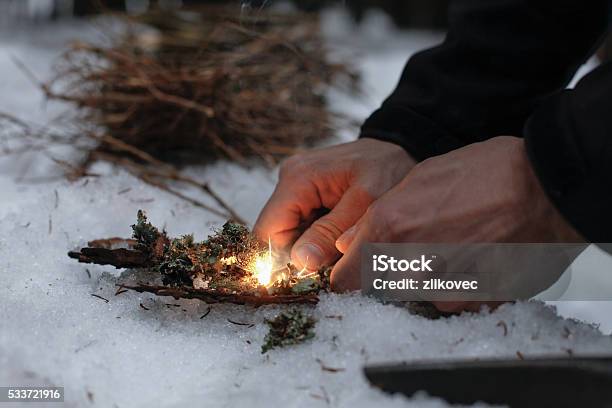 Man Lighting A Fire In A Dark Winter Forest Stock Photo - Download Image Now - Fire - Natural Phenomenon, Beginnings, Snow