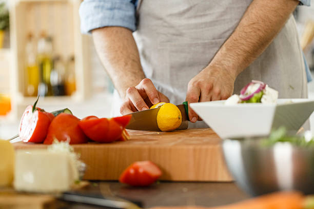 istock Man cutting lemon, preparing healthy salad 533722578