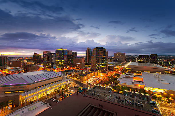 Phoenix Skyline, Arizona A view of downtown Phoenix at night. On the left the Phoenix stadium and high rises on the horizon taken with long exposure from a balcony. The warm yellow lights from the buildings against the blue sky make for a dramatic city scape. phoenix arizona stock pictures, royalty-free photos & images