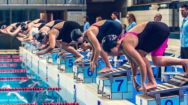 istock Female swimmers crouching on starting block ready to jump 533725438