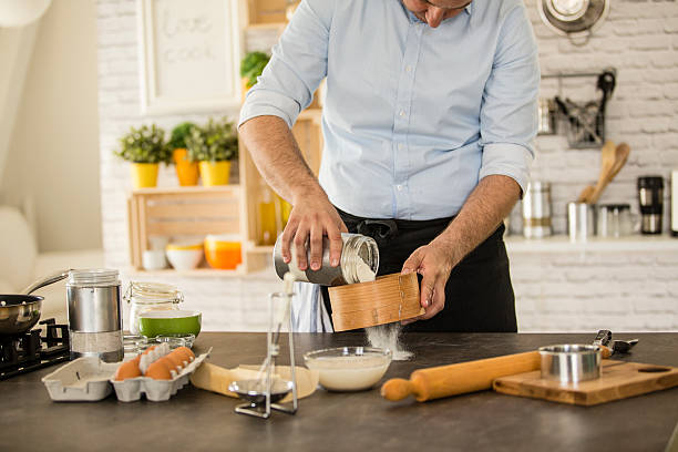 istock Man sieving flour on the kitchen counter, making dough 533728732