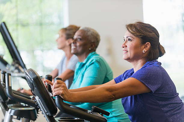 herren damen auf heimtrainern im fitness-center - aerobics stock-fotos und bilder