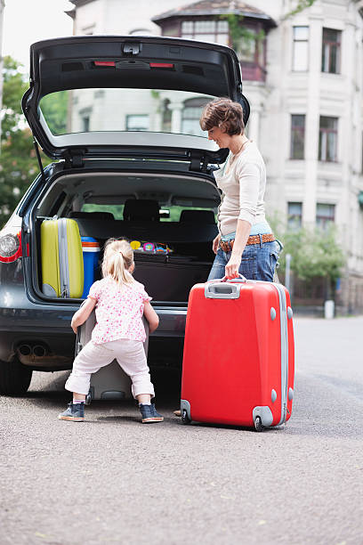 istock Mother and daughter loading luggage into car 533744033