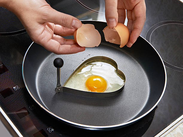 istock Woman preparing fried eggs in heart form 533745079