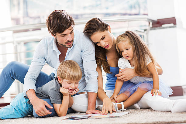 Young family reading magazine. Young parents enjoying with their children while teaching them hot to read. lifestyles teaching little girls child stock pictures, royalty-free photos & images