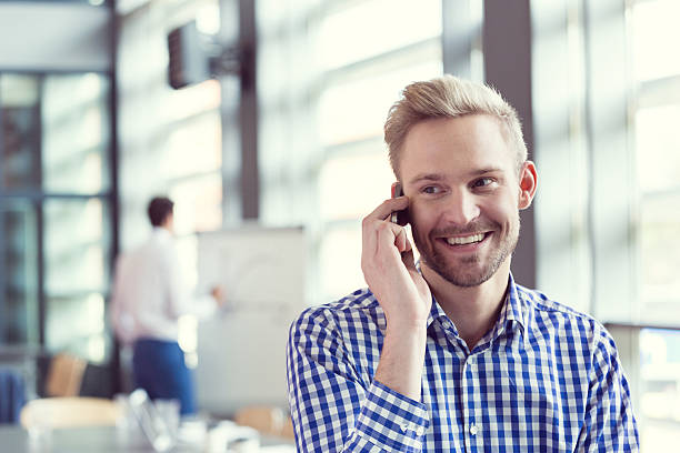 uśmiechająca się biznesmen mówić na inteligentny telefon - thinking business ceo board room zdjęcia i obrazy z banku zdjęć