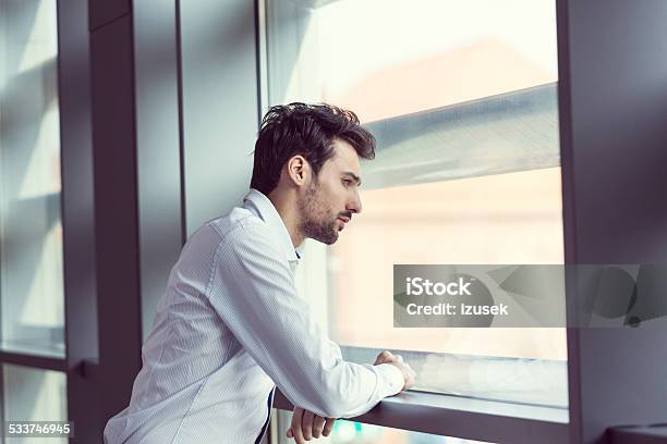 Young Businessman Looking Out The Window Stock Photo - Download Image Now - Businessman, Elegance, 2015