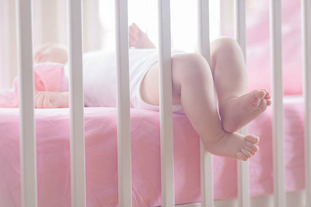 baby's ноги высовывать через rails из детская �кроватка. - railing beautiful human leg people стоковые фото и изображения