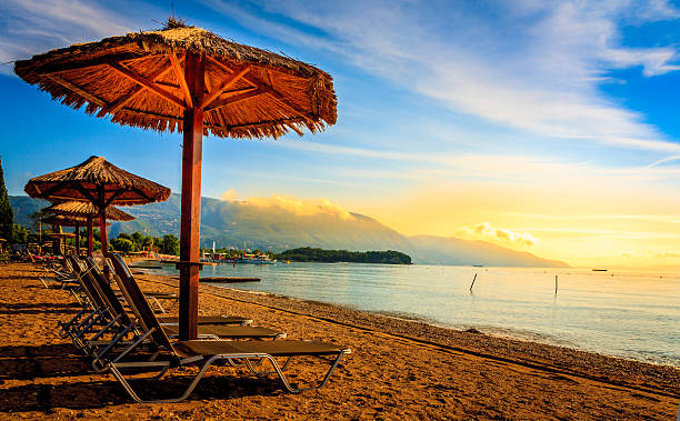 Corfu island Greece beach Summer beach and row of umbrellas. Sunrise. Corfu island. Greek islands.  corfu stock pictures, royalty-free photos & images