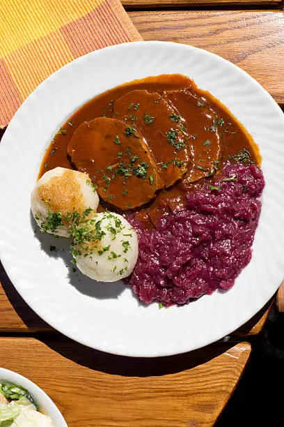 Sauerbraten with red cabbage and potatoe dumplings on plate