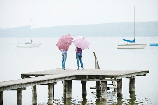 Bavaria, Ammersee two Women standing on jetty holding umbrellas