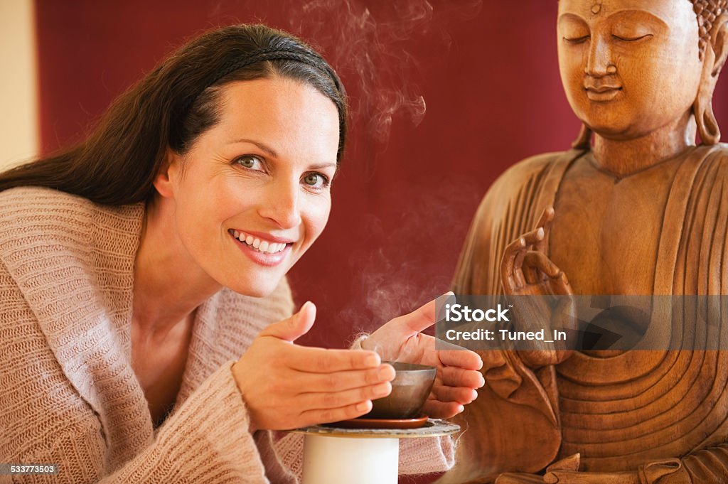 Brunette woman enjoying joss stick's scent buddha statue in background 2015 Stock Photo