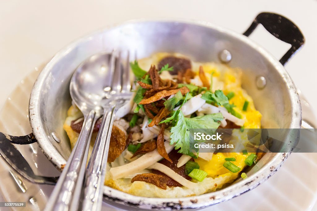 fried egg with white pork sausage,crispy pork,parsley fried egg with white pork sausage,crispy pork,parsley,spring onion serving in a little pan 2015 Stock Photo