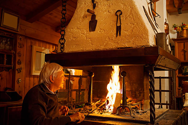 istock White-haired senior man enjoys, makes fire in the fireplace  Chalet 533832961