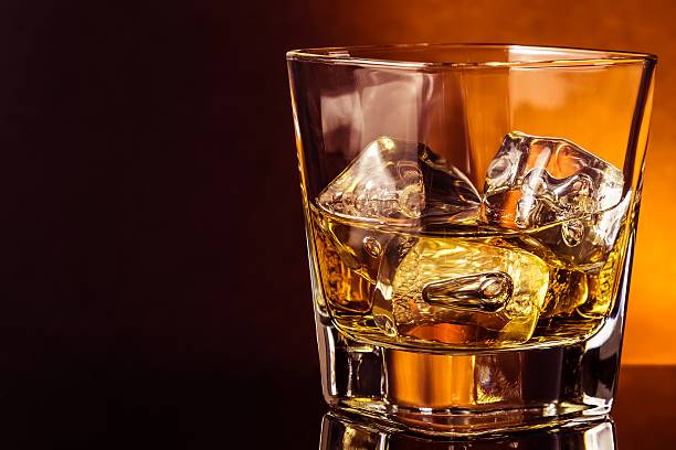 istock glass of whiskey on black table with reflection, warm atmosphere 533833810