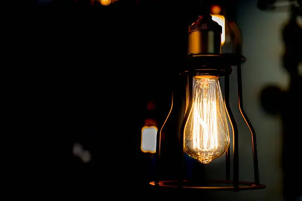 Edison bulb glowing in the dark blurred background