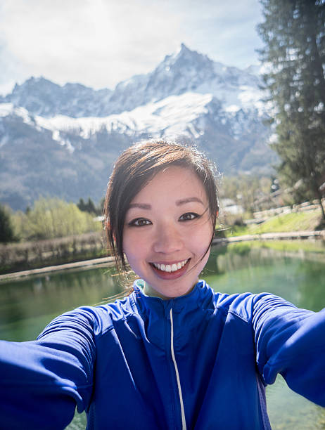 Woman taking a selfie while running outdoors Young Asian woman taking a selfie while running outdoors and looking very happy photographing herself stock pictures, royalty-free photos & images
