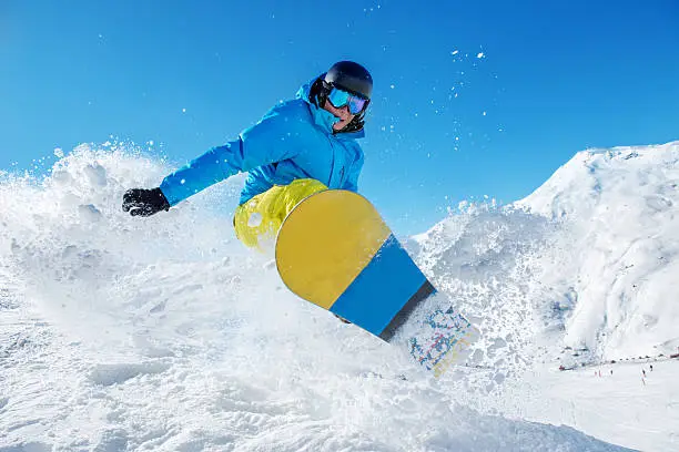 Active snowboarder jumping in winter mountains