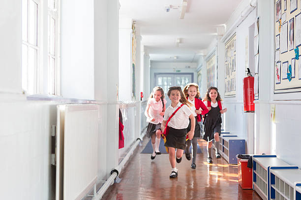 Ecstatic Schoolgirls Small group of schoolgirls running down the corridor of a school. The girls look ecstatic with smiles on their faces. They are wearing school uniform carrying their schoolbags. cardigan wales stock pictures, royalty-free photos & images