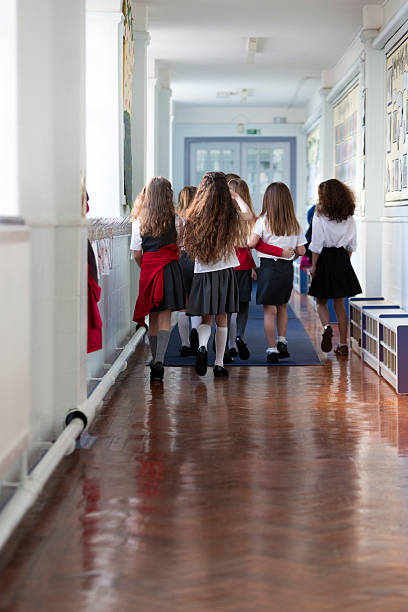 Group of children running towards a teacher and blackboard isolated on white background