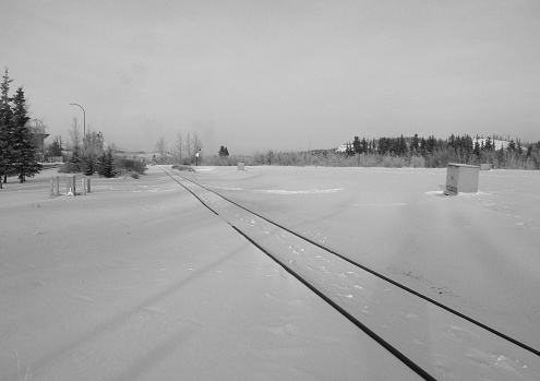 Whitehorse, Yukon, Canada - December 3rd, 2013: winter peaceful landscape crossed by the almost undetected railway on the way north, through Whitehorse town centre.