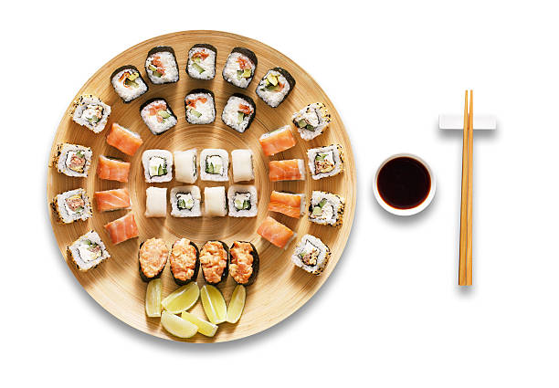 Set of sushi maki and rolls isolated at white. Japanese food restaurant, sushi maki gunkan roll plate or platter set. Chopsticks, ginger, wasabi and soy sauce. Sushi at bamboo round plate isolated at white background. japanese cuisine food rolled up japanese culture stock pictures, royalty-free photos & images
