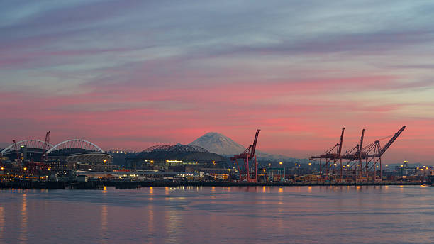 Seattle Port and Stadiums in the Evening Centurylink field and Safeco field can be seen across Elliott Bay (left and right stadiums, respectively), with the port of Seattle on the right and Mt. Rainier in the background. elliott bay photos stock pictures, royalty-free photos & images