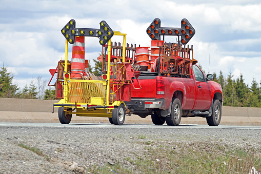 Truck and trailer transporting traffic control equipment to a road construction site.