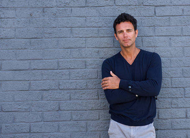 istock Mature man standing against gray wall with arms crossed 533855462