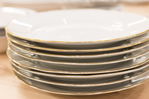 Garage sale (flea market) with a stack of second-hand, old white plates with golden edges.