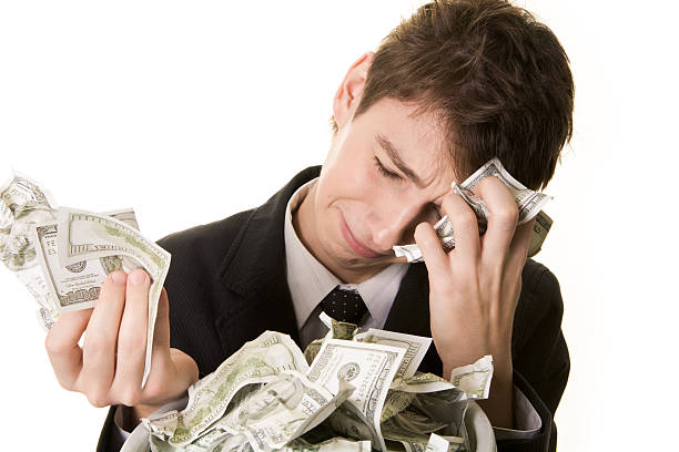 The money has simply vanished Conceptual image of grieving young businessman over heap of crumpled dollars money cry stock pictures, royalty-free photos & images