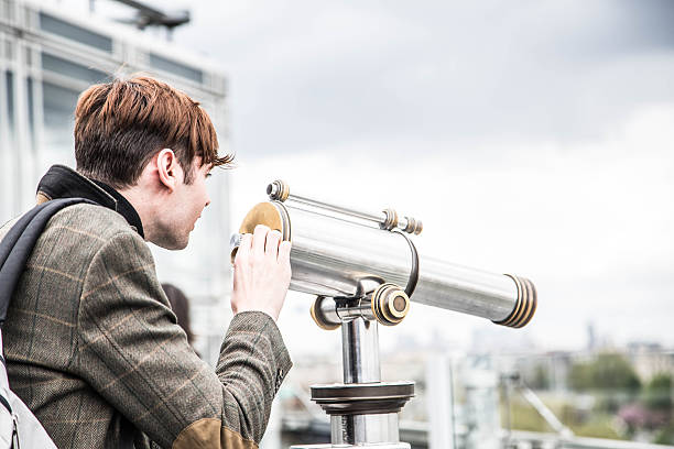 istock handsome young man looking through telescope at  Paris skyline 533895090