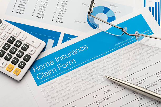 Home insurance claim form on a desk with paperwork. Home insurance claim form on a desk with paperwork. There is also a pen and calculator on the desk household insurance stock pictures, royalty-free photos & images