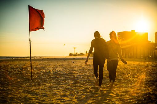 Two tennager girls walks at sunset at the Brighton Beach, Coney Island, Brooklyn, New York, USA.