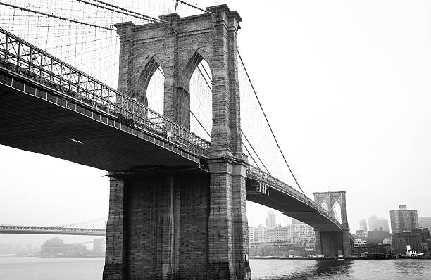 View Brooklyn Bridge with Foggy City in the Background View Brooklyn Bridge with Foggy City in the Background in Black and White brooklyn bridge photos stock pictures, royalty-free photos & images