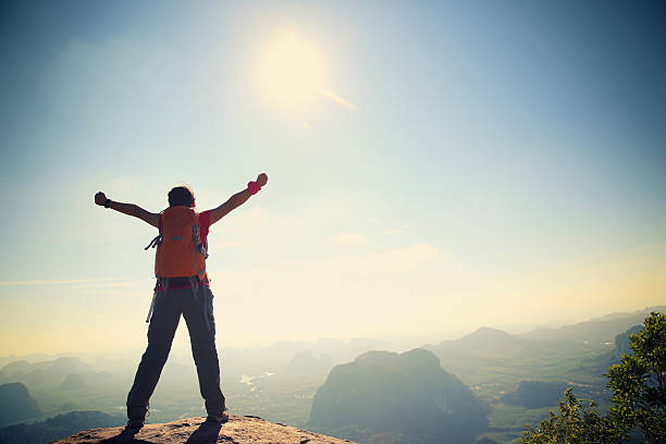 istock cheering woman hiker open arms at mountain peak 533898914