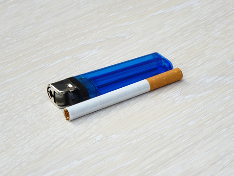 Lighter and cigarette laying flat on a wooden surface.