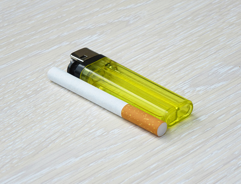 Lighter and cigarette laying flat on a wooden surface.