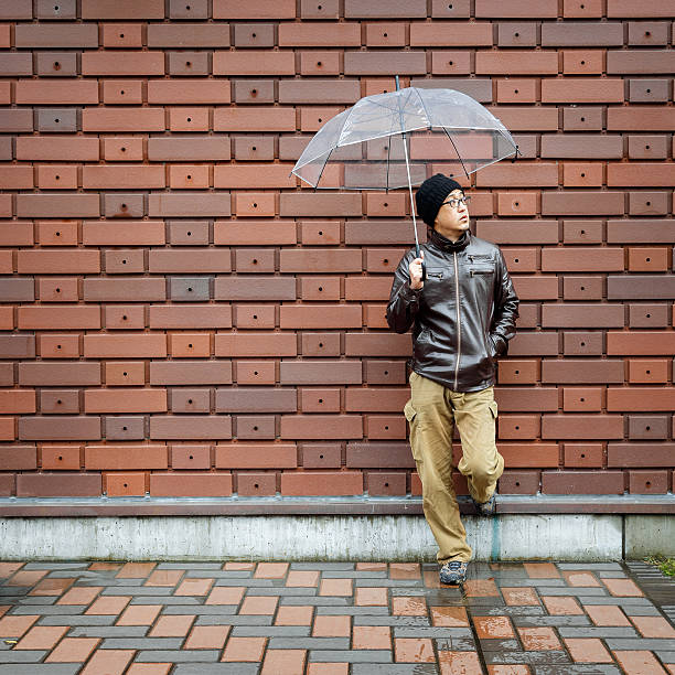 istock Asian Man in a Brown Jacket With a Clear Umbrella 533903480